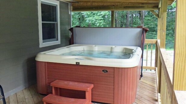 A hot tub on a wooden deck with a window and a small wooden stool. - The Pine Ridge Home by Garden of the Gods in the Shawnee National Forest (Herod)