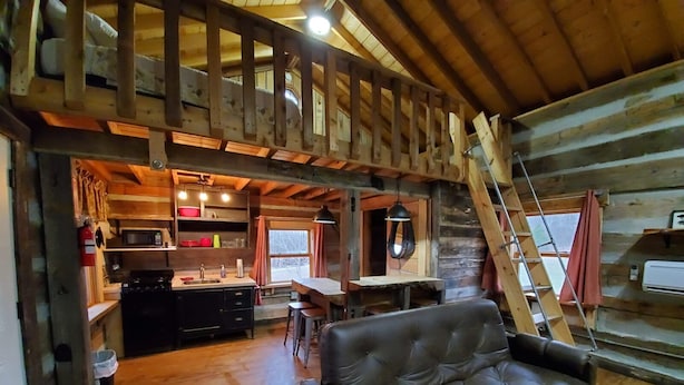A cozy cabin interior with a kitchen, dining area, and a living room with a sofa.