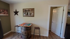 A room with a wooden barrel table, two stools, a star decoration, and a framed picture on the wall.