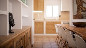 Een moderne keuken met houten kastjes, een eettafel met stoelen en een grote schaal op de tafel.