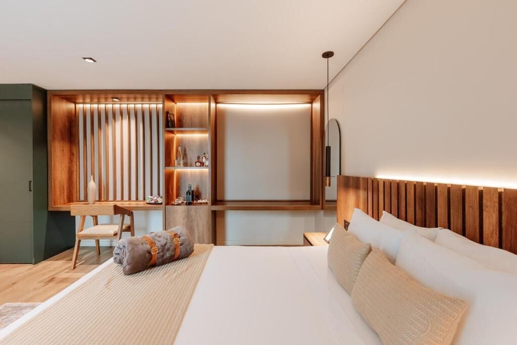 Una habitación de hotel moderna con cama, escritorio y estantería empotrada.