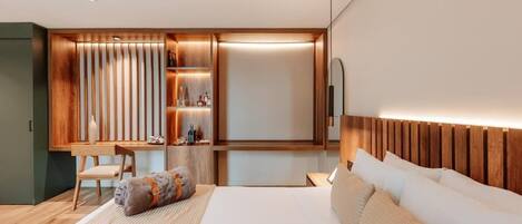 A modern hotel room with a bed, a desk, and a built-in shelf unit.