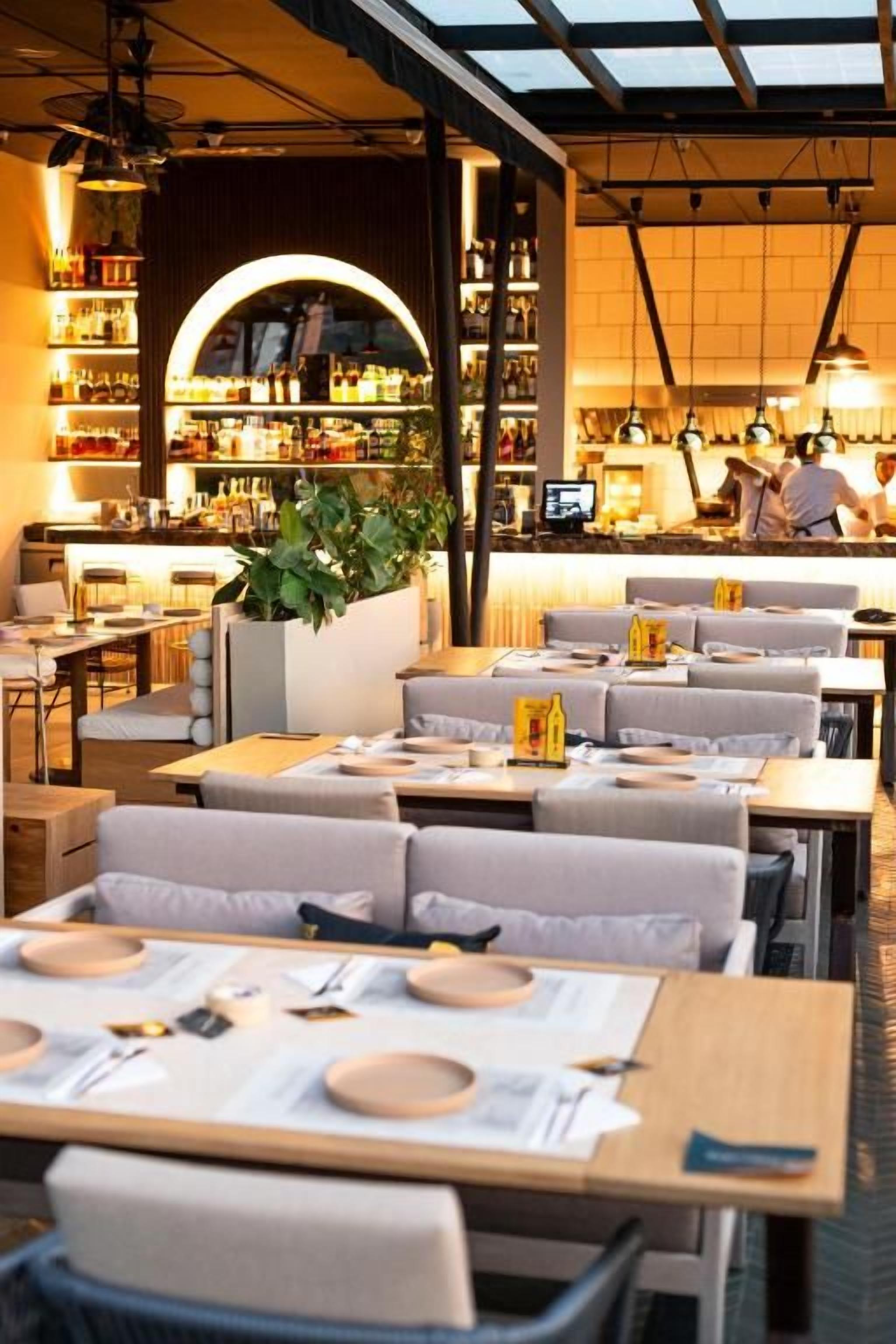 En restaurant med dækketøjsbestik, et barområde og en siddeafdeling med polstrede stole.