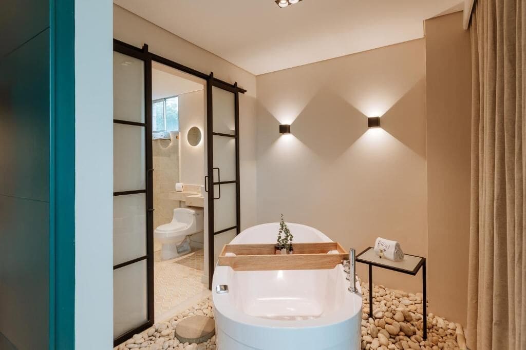 A modern bathroom with a freestanding bathtub, a glass shower enclosure, and a small side table with a towel.