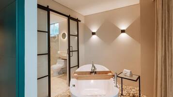 A modern bathroom with a freestanding bathtub, a glass shower enclosure, and a small side table with a towel.