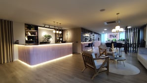 A modern interior with a reception desk, wooden flooring, and a dining area with chairs and a table. - 1616 HOTEL  (Medellín)