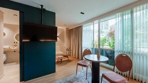 A modern living room with a round table, two chairs, a sofa, and a large window with curtains. - 1616 HOTEL  (Medellín)