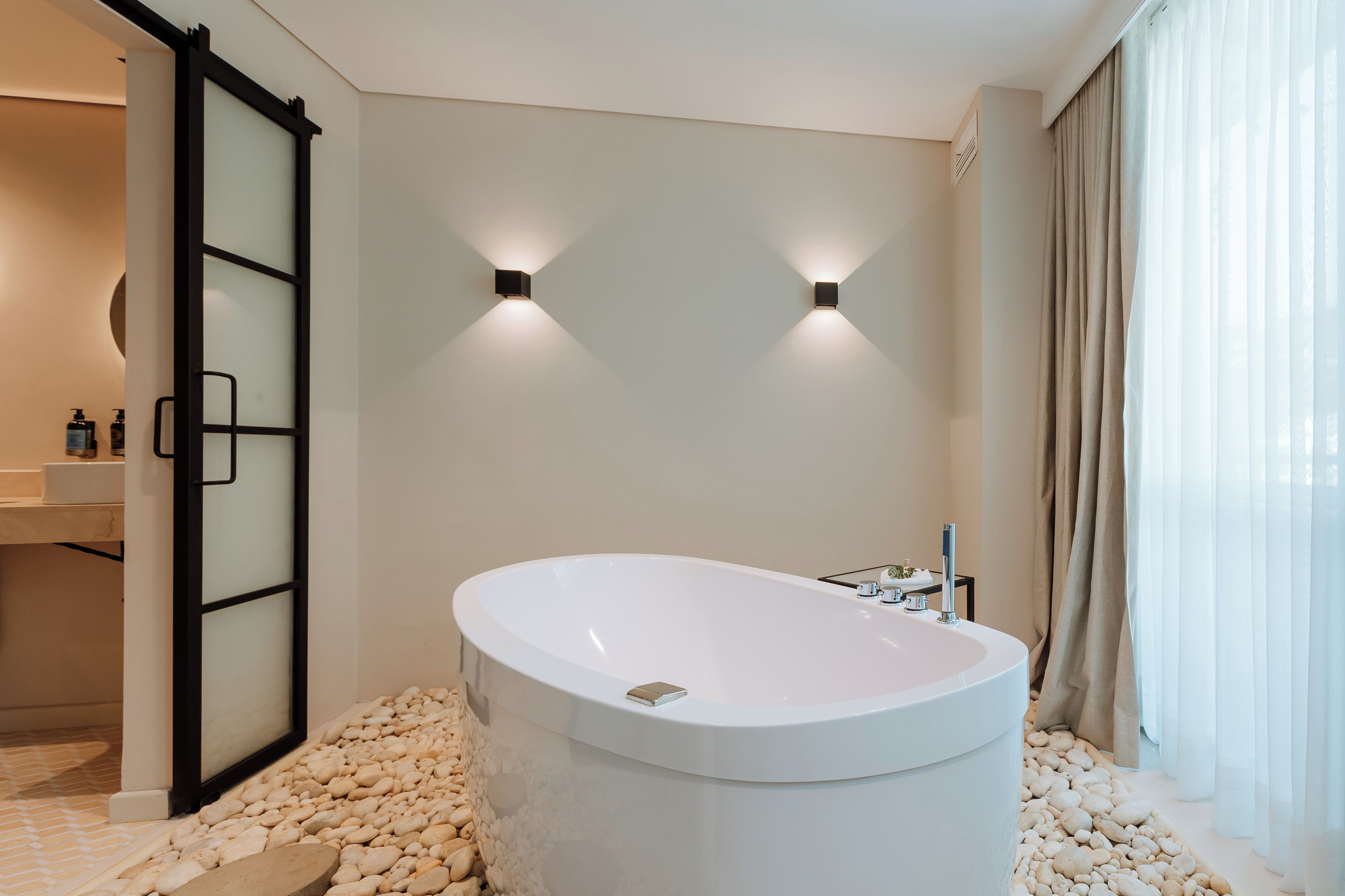 Un baño moderno con una bañera independiente, cabina de ducha de vidrio y tocador con lavamanos y espejo.