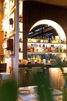 Un espace bar avec des étagères remplies de bouteilles, un comptoir et une vue par la fenêtre.