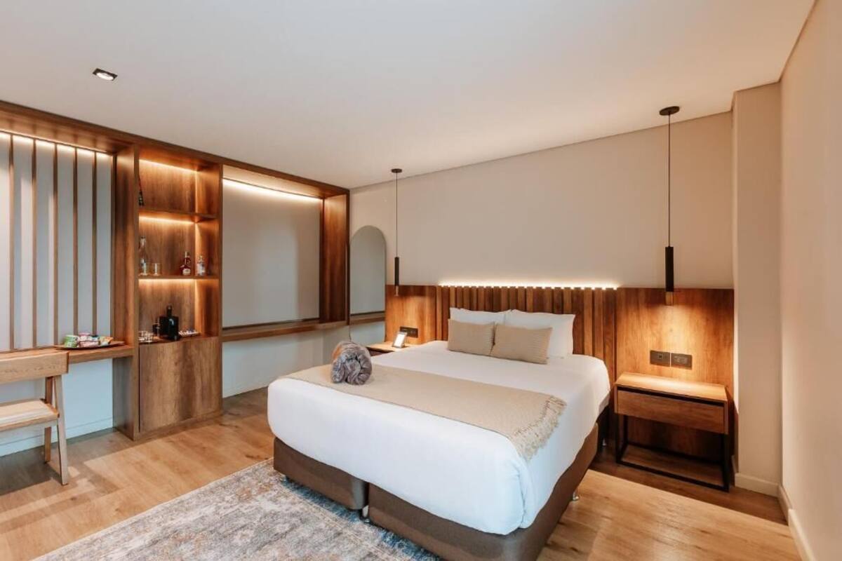 A modern bedroom with a large bed, bedside tables, a desk, and a mirror.