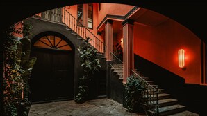 A grand staircase with a black railing and a red-lit wall, leading to an upper floor. - Palazzo Flora (Gallipoli)