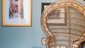 A room with a wicker chair, a framed picture, and a wall-mounted lamp. - Palazzo Flora (Gallipoli)