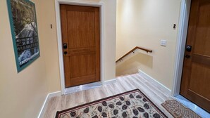 Un pasillo con una puerta de madera, un cartel en la pared, una alfombra y una señal de salida.
