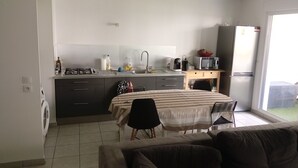 Ein kompakter Wohnraum mit Küchenzeile, Essbereich und einer Couch.