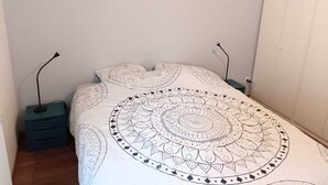 Ein Schlafzimmer mit einem großen Bett, zwei Nachttischen, einem Kleiderschrank und einer Stehlampe.
