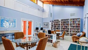 Une pièce spacieuse avec une grande bibliothèque, une table en verre et des sièges confortables.