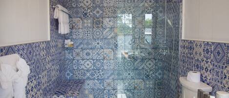 A bathroom with a shower, toilet, and sink, featuring blue and white patterned tiles.