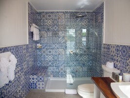 A bathroom with a shower, toilet, and sink, featuring blue and white patterned tiles.