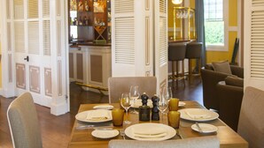 Un coin repas avec une table dressée pour quatre personnes, comprenant des assiettes, des couverts et des verres.