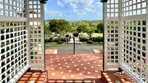 Un pavillon ouvert, doté d’un sol carrelé et offrant une vue sur un jardin aménagé.