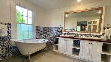 A bathroom with a freestanding bathtub, a large mirror above the sink, and patterned tile walls.