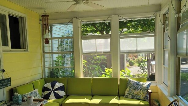 Una habitación acogedora con un sofá verde, un sillón de balancín de madera y una mesita pequeña.
