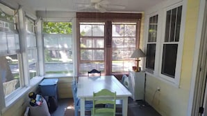Una habitación con una mesa de comedor, sillas, un ventilador de techo y ventanas amplias.