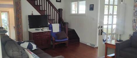 A living room with a staircase, a television, a sofa, and a lamp.