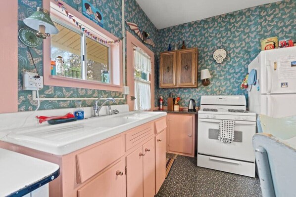 A vintage kitchen with a white stove, wooden cabinets, and a sink.