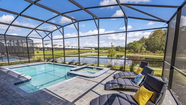 Un espace de baignade extérieur abrité, comprenant une piscine et un jacuzzi, entouré de chaises longues avec des coussins.
