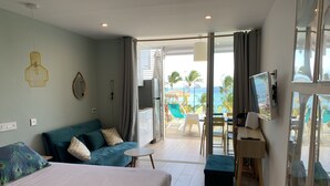 Habitación de hotel con cama, sofá, escritorio y vista al océano.