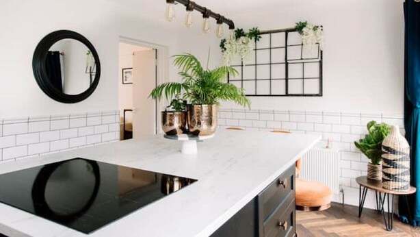 A modern kitchen with a white countertop, black induction cooktop, and two gold-colored pots. - Modern & Stylish Home in the Heart of Belfast (Belfast)