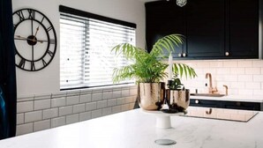 A modern kitchen with a marble countertop, a large clock, and potted plants. - Modern & Stylish Home in the Heart of Belfast (Belfast)