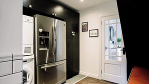 A compact kitchen with a stainless steel refrigerator, a built-in oven, and a washing machine. - Modern & Stylish Home in the Heart of Belfast (Belfast)