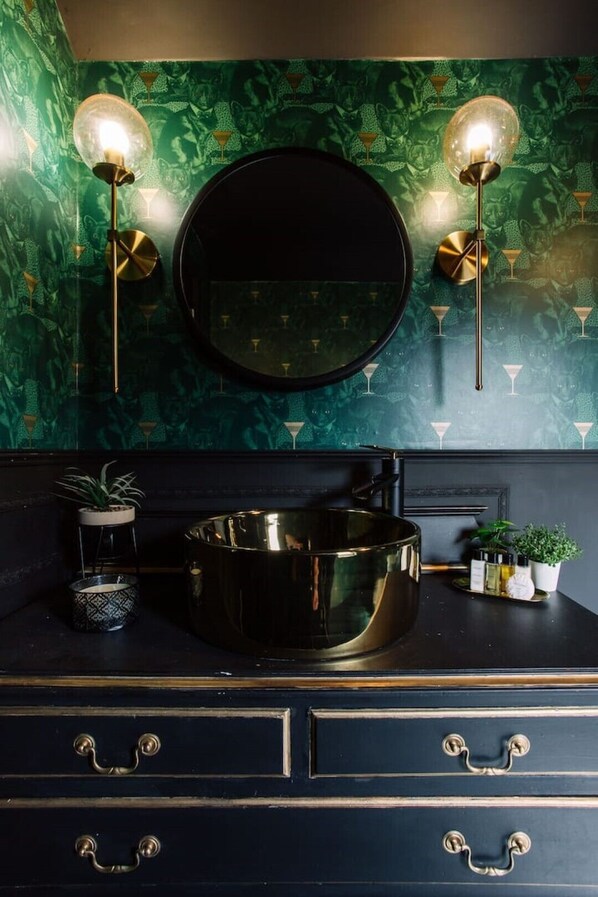 A bathroom with a black vanity, a round mirror, and two wall-mounted lights. - Stylish Designer 4-Bed Home in the Heart of Belfast (Belfast)