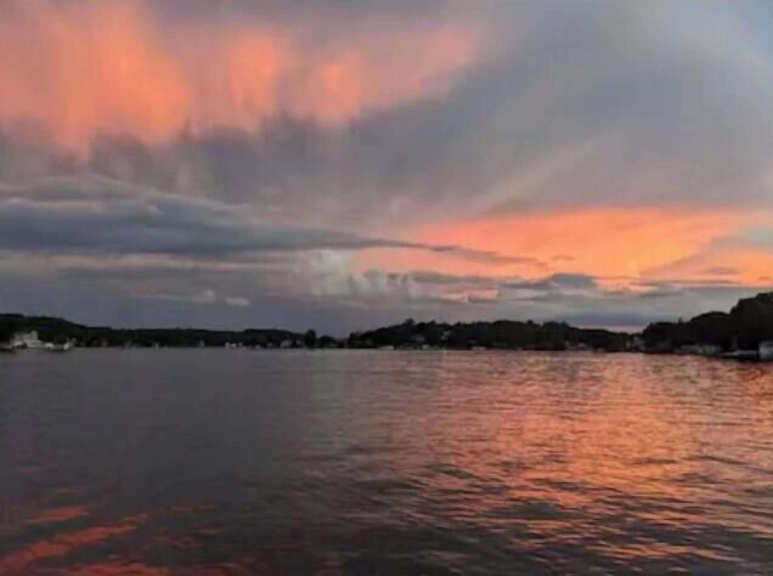 A sunset over a body of water with a distant shoreline.