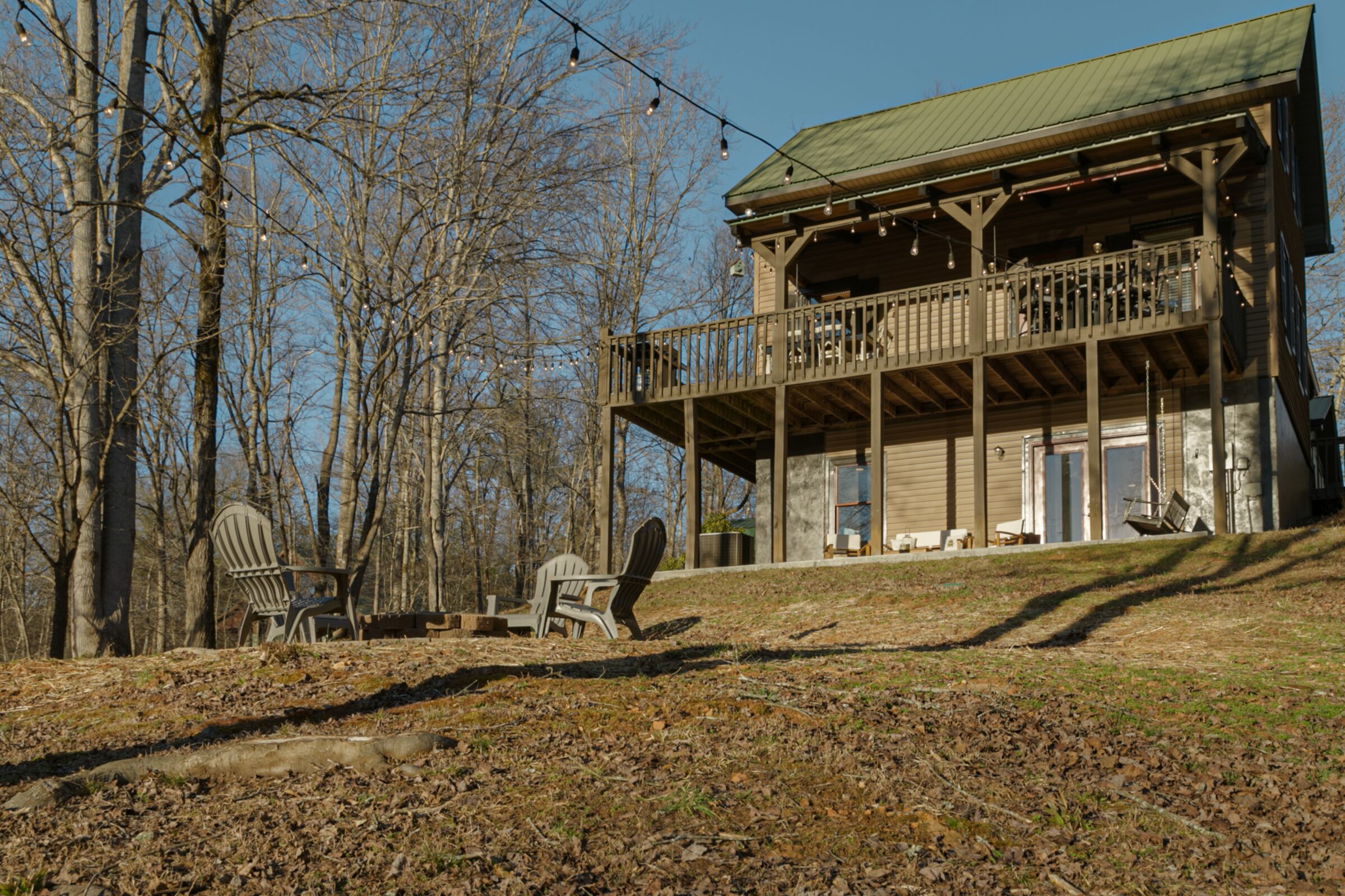 A two-story wooden cabin with a balcony, surrounded by trees.