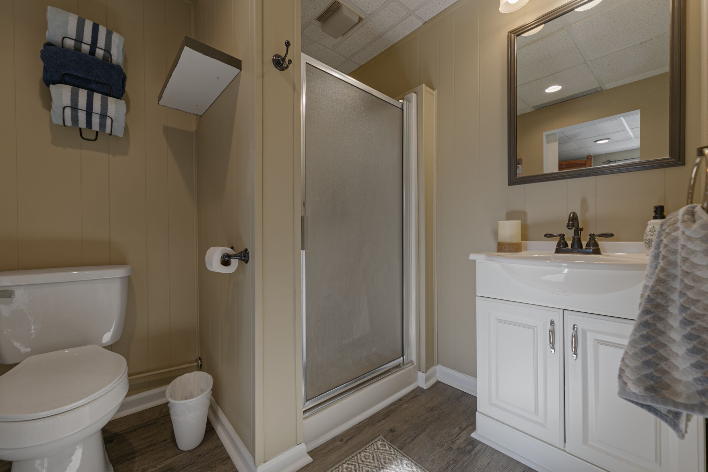 A bathroom with a toilet, a shower enclosure, a sink, and a mirror.
