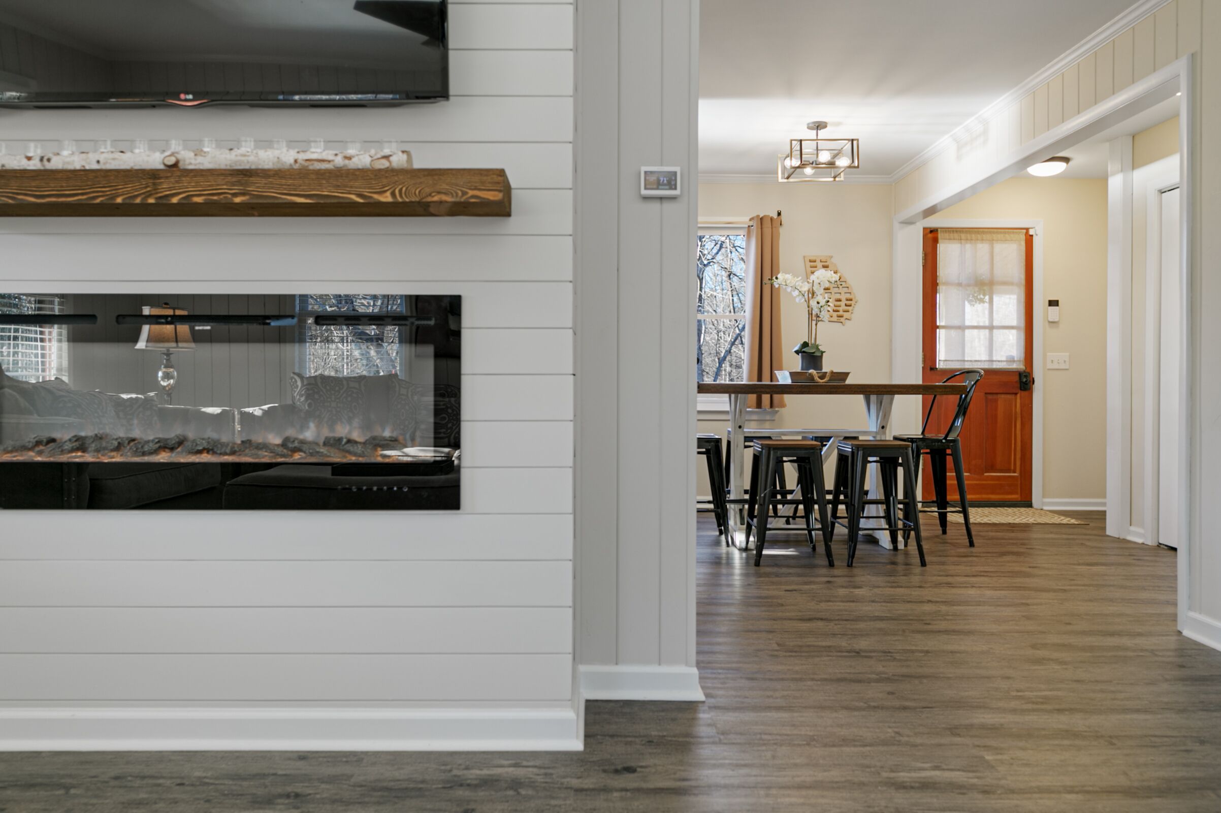 Una cocina moderna con chimenea integrada, estantes de madera y un comedor con mesa y sillas.