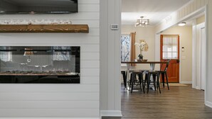A modern kitchen with a built-in fireplace, wooden shelves, and a dining area with a table and chairs. - Wine Country Lake Escape-Fishing and Hot tub (Cleveland)