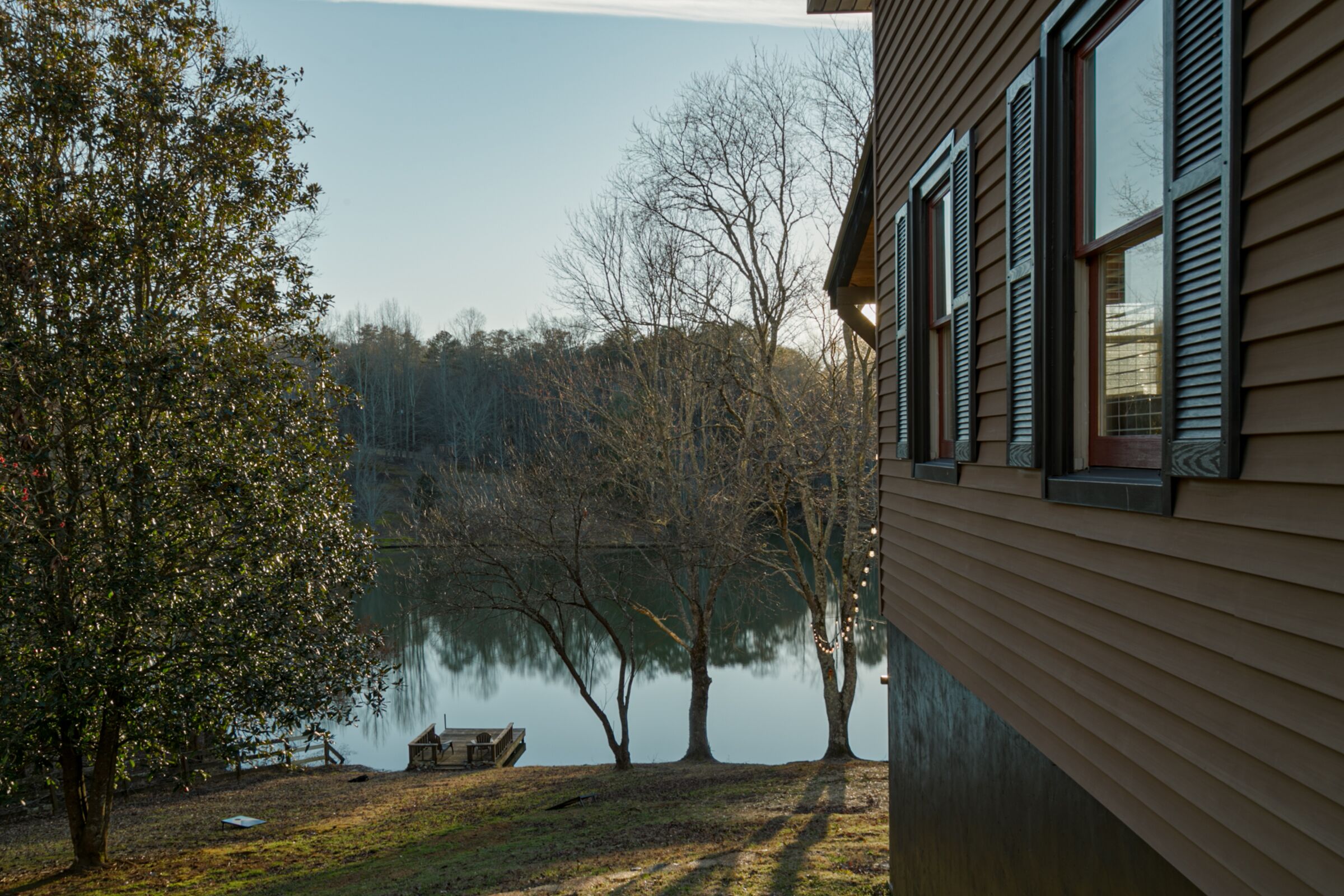 Una casa con vista su un lago, alberi e un molo.
