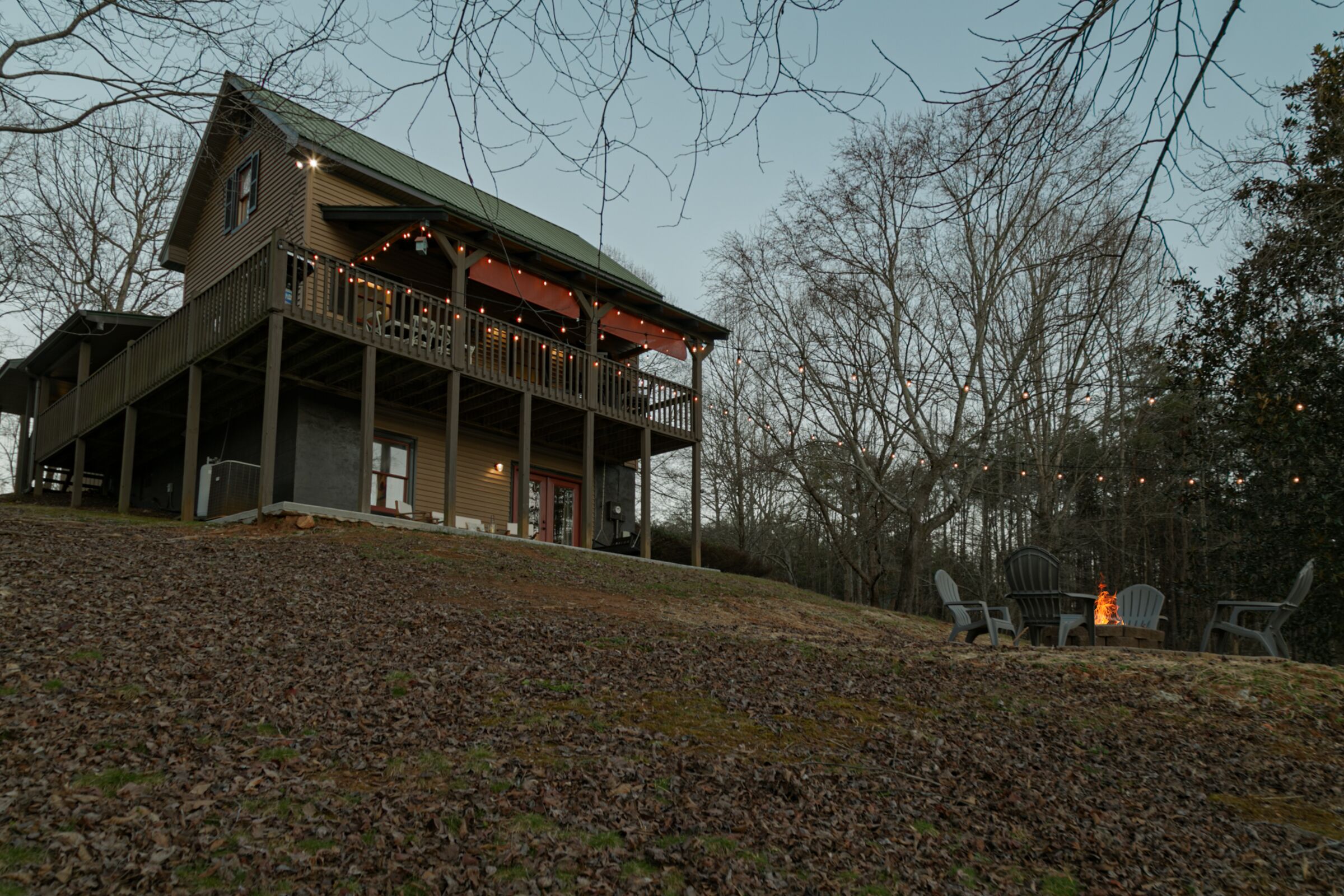 A cabin with a balcony, a fire pit, and outdoor seating.