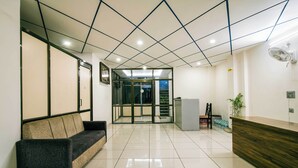 A reception area with a wooden reception desk, a black and beige sofa, and a glass door leading to a staircase. - Treebo Paras Raj Near City Palace (Udaipur)