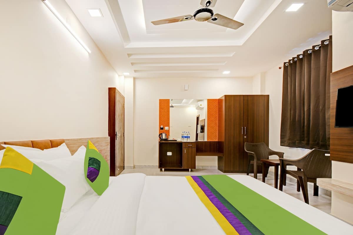 A hotel room with a bed, a desk, a chair, a wardrobe, and a television.