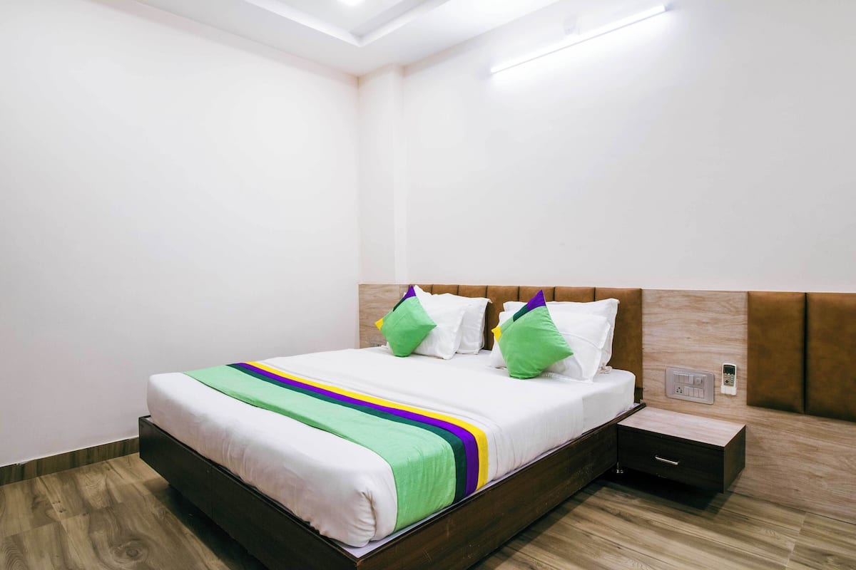 A neatly made bed with a striped bedspread, a bedside table, and a wall socket.