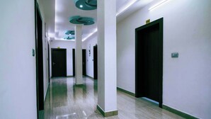 A hallway with white walls, dark doors, and a shiny floor. - Treebo Paras Raj Near City Palace (Udaipur)