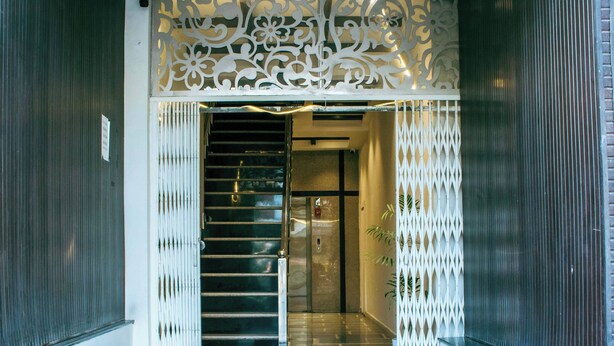 A modern entrance with a decorative white partition, a staircase, and a glass door leading to an interior space. - Treebo Paras Raj Near City Palace (Udaipur)