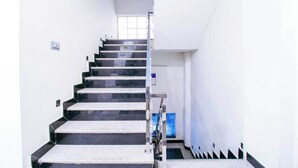 A staircase with a handrail, white walls, and a window at the top. - Treebo Paras Raj Near City Palace (Udaipur)