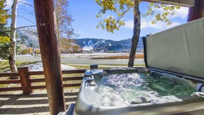 Un jacuzzi con cubierta de madera y vista a un paisaje nevado de montañas.
