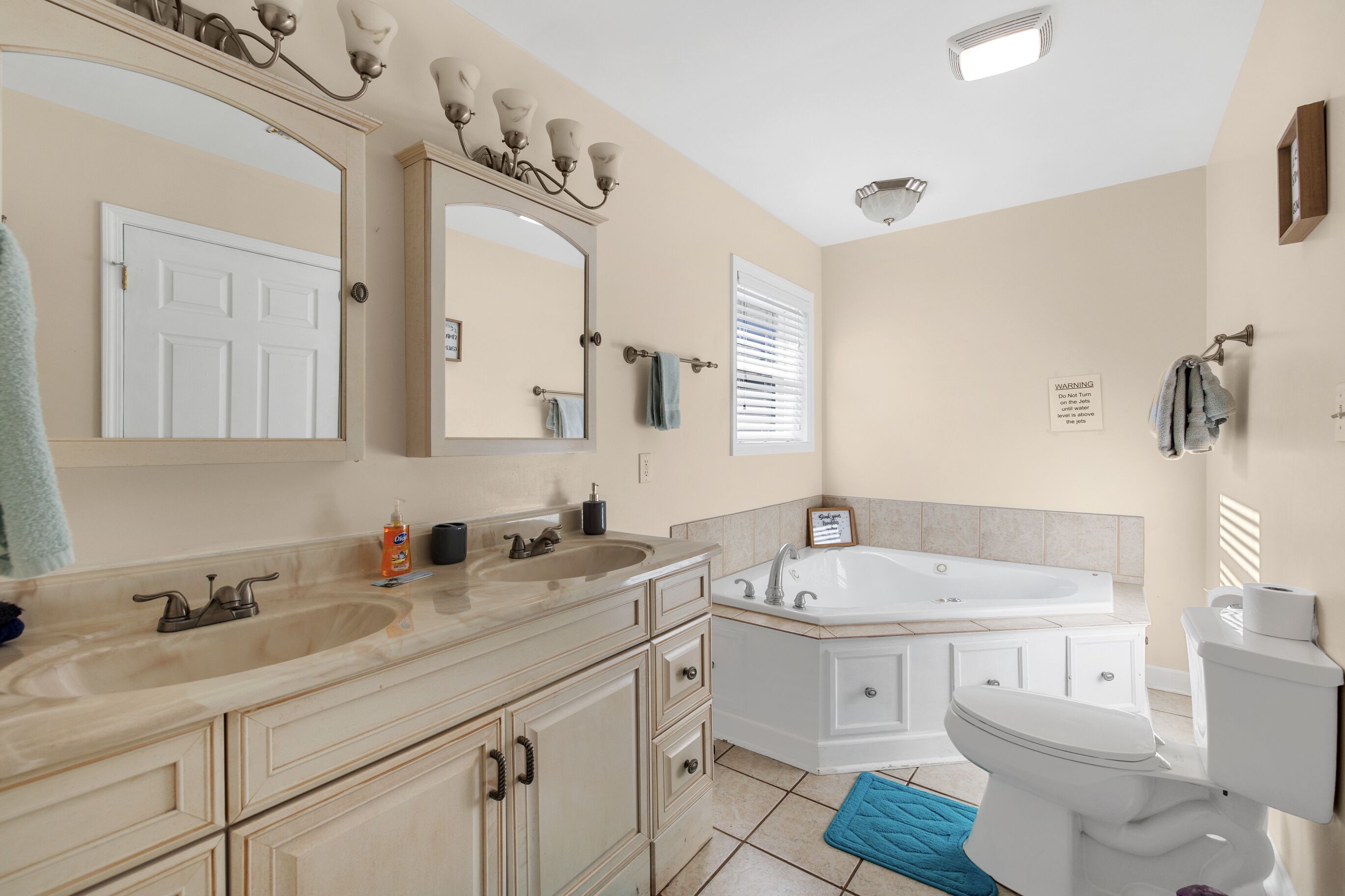 A bathroom with a double sink vanity, a bathtub, and a toilet.